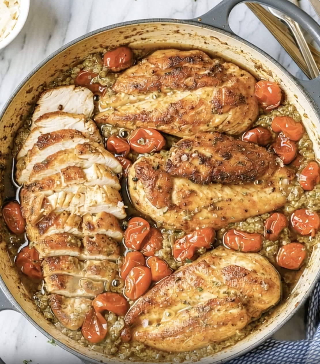 A pot of chicken with tomatoes and peppers.